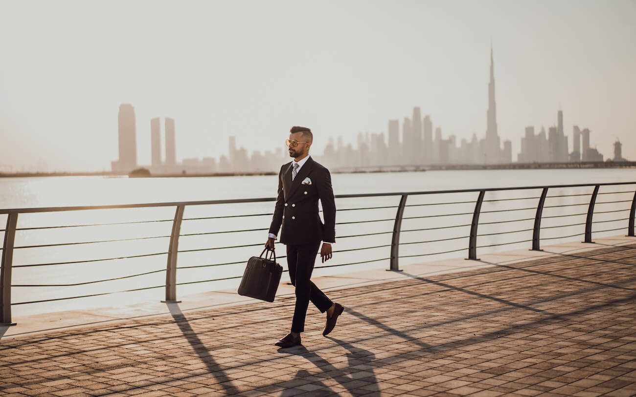 Professional walking along a waterfront with a city skyline behind